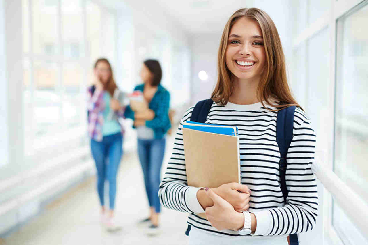 vantagens-faculdade-semipresencial - mulher com livros em corredor da faculdade