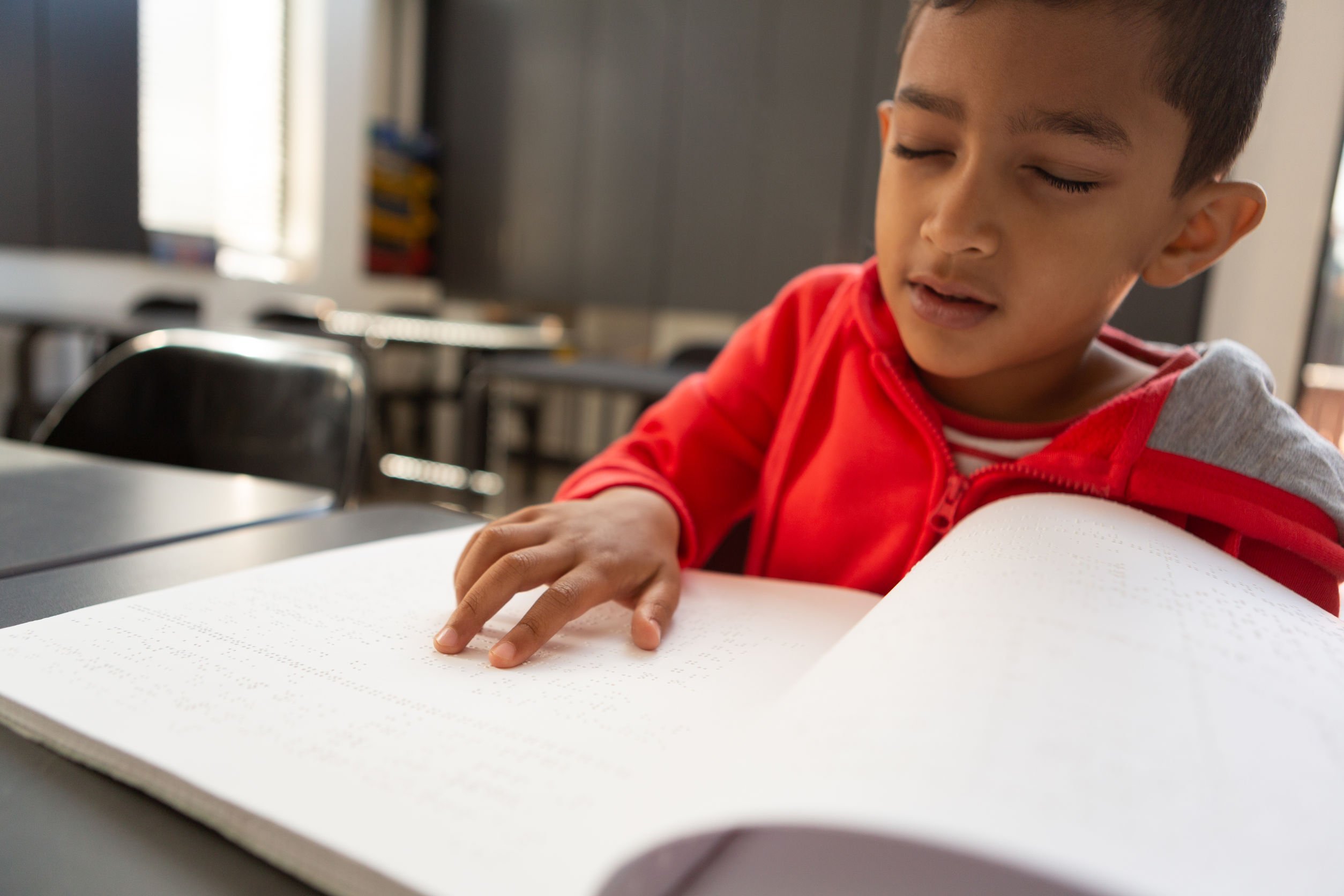 atendimento educacional especializado - menino lendo livro em braile